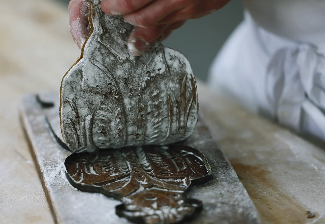 Traditionally soft dough was pressed into wooden molds to build shape. However, a change in the recipe made the dough more solid, leading bakers to dispense with the molds and simply cut it into the desired shapes. 